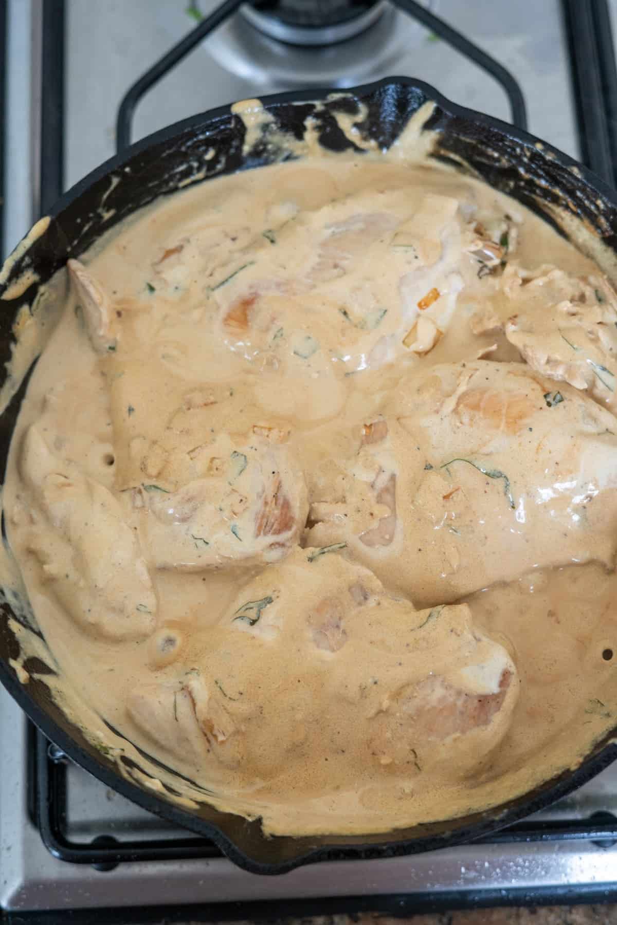 Tarragon chicken cooked in a skillet with a creamy sauce.