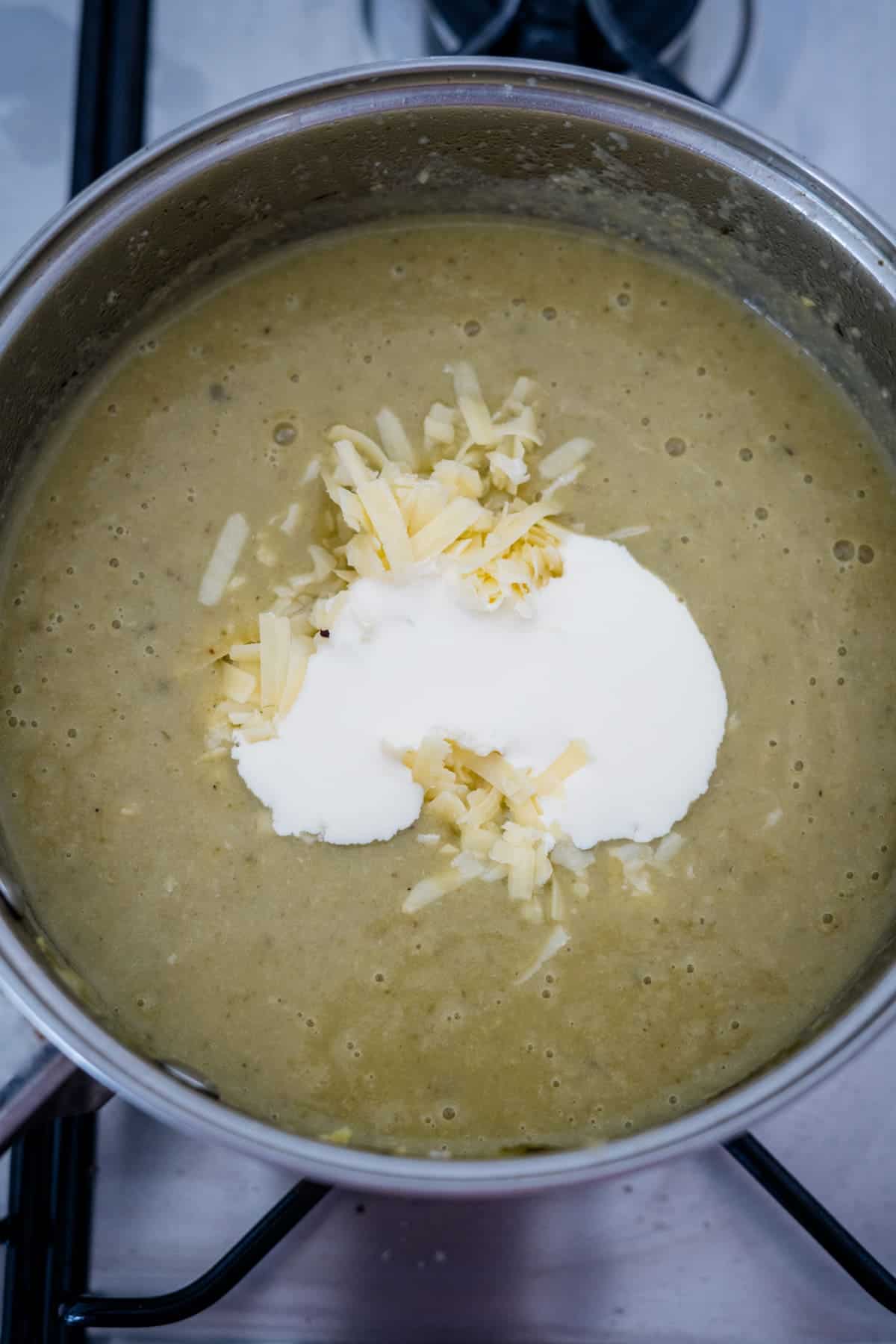 A pot of brussel sprout soup on a stove with cheese on top.