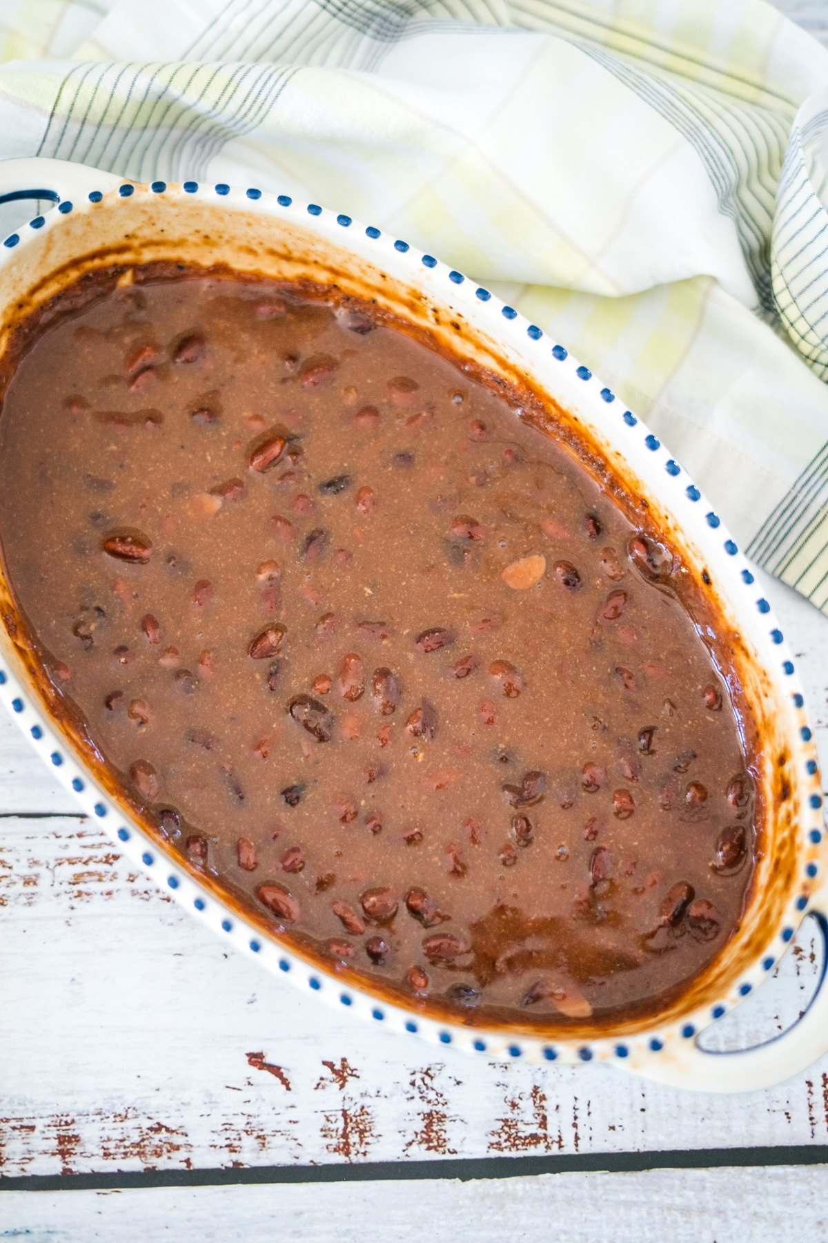 A casserole dish with beans and sauce on a wooden table.