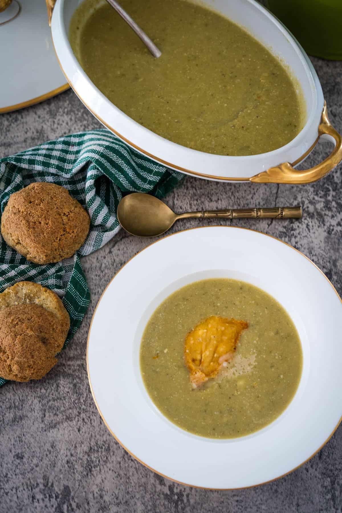 A bowl of brussel sprout soup and a bowl of bread on a table.