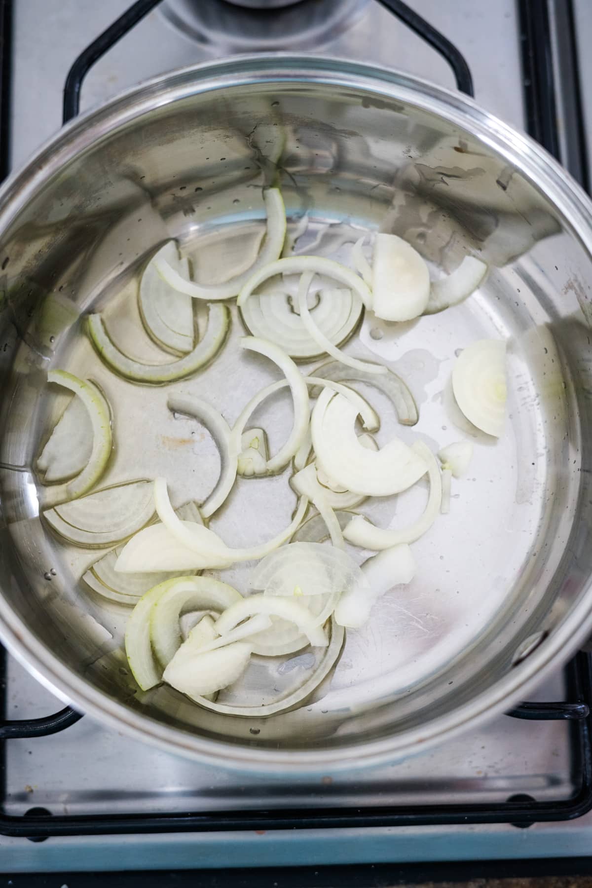 Sliced onions in a pan on top of a stove.