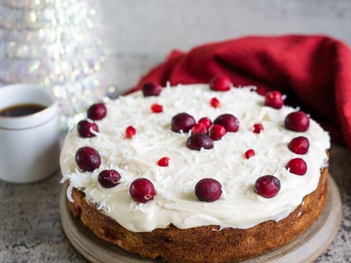 A cake with cranberries and cream on top.