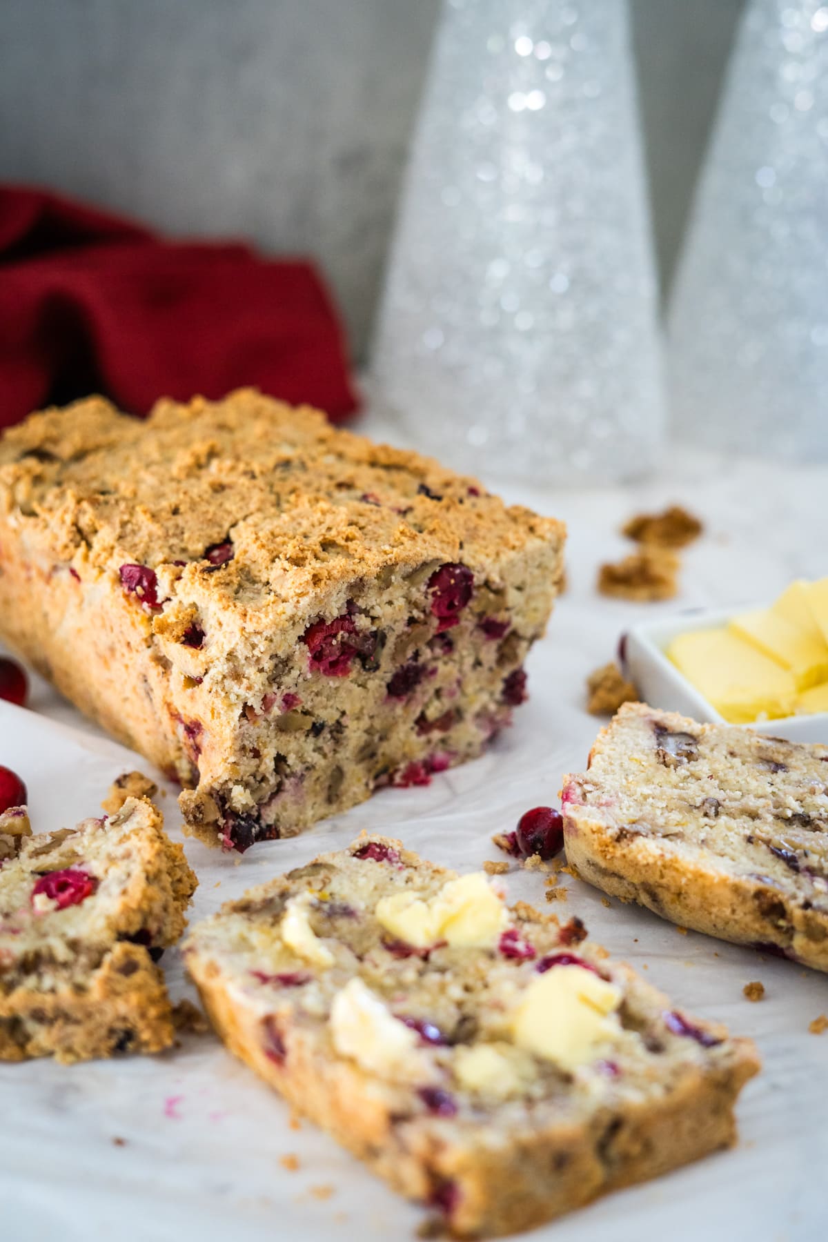 A loaf of cranberry walnut bread on a white plate.