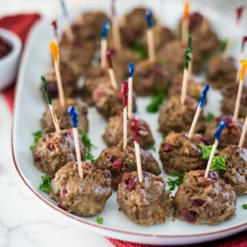 Cranberry meatballs with toothpicks on a plate.