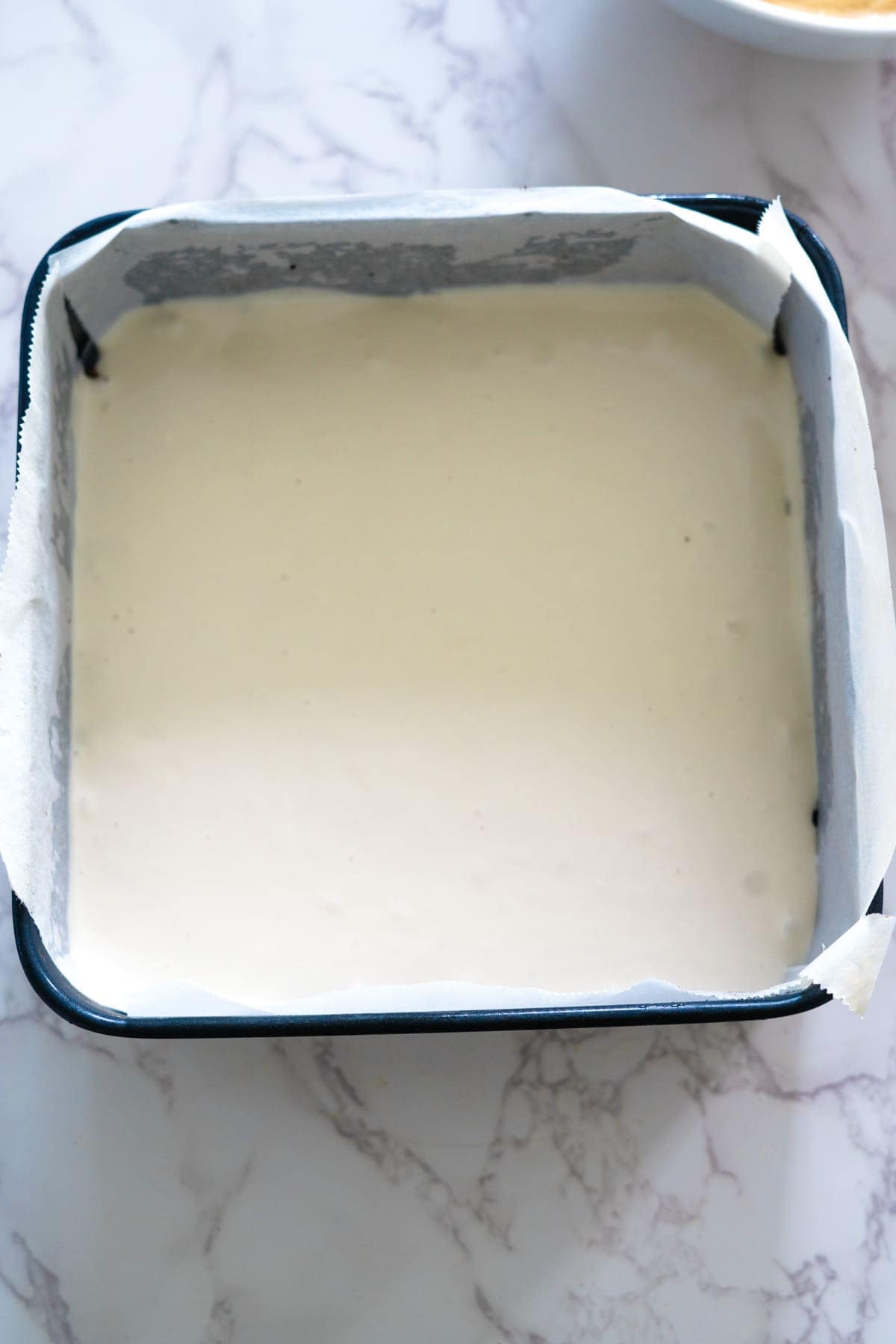 A white cake in a baking pan on a marble counter.