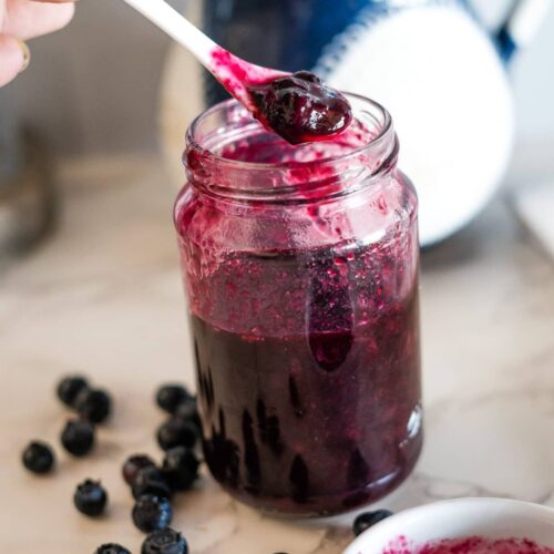 Blueberry jam in a jar with a spoon.