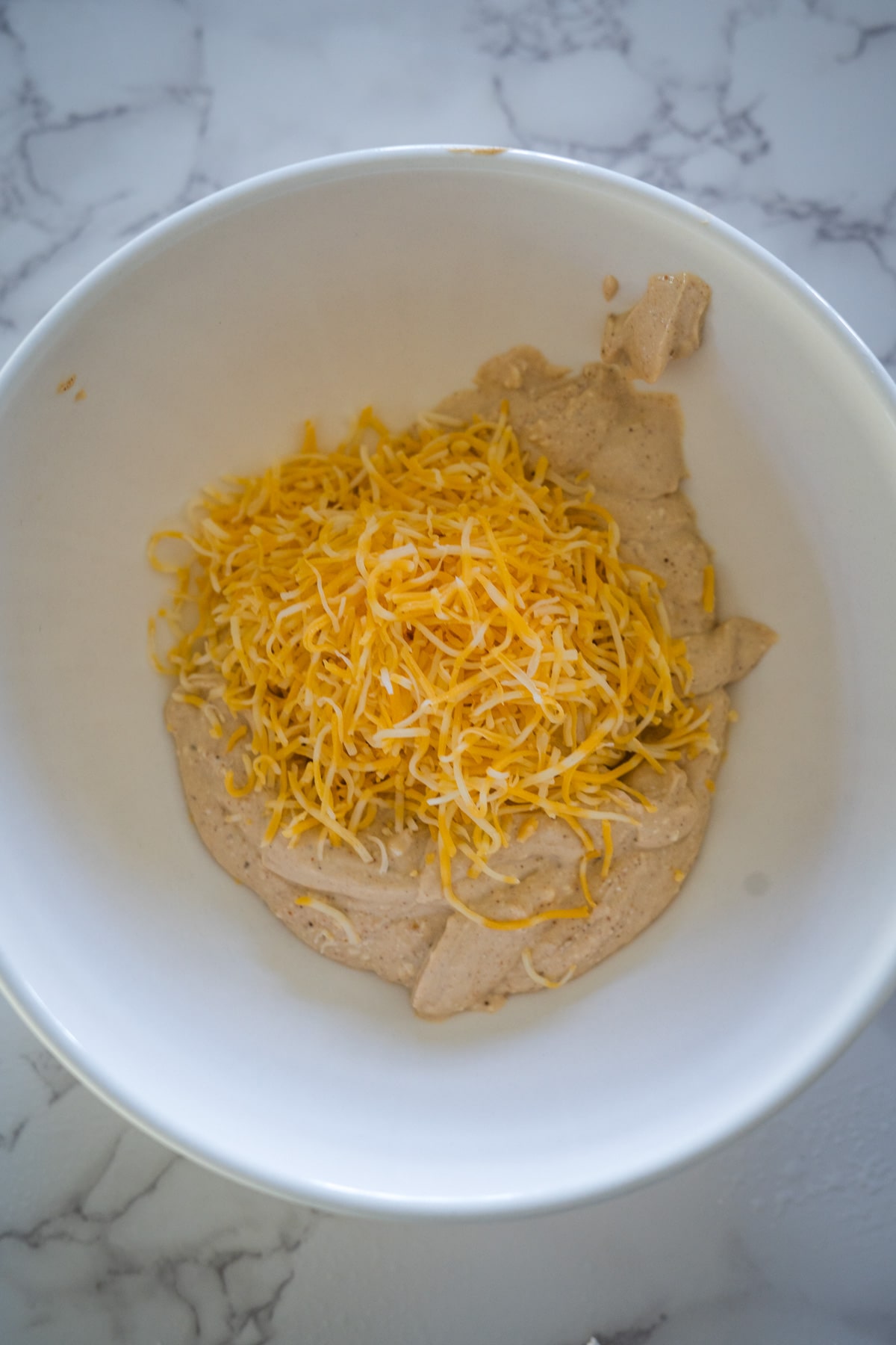 A bowl of queso dip with cheese in it.