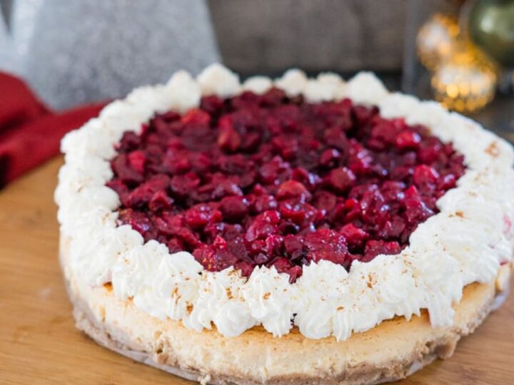 A cranberry cheesecake on a wooden cutting board.