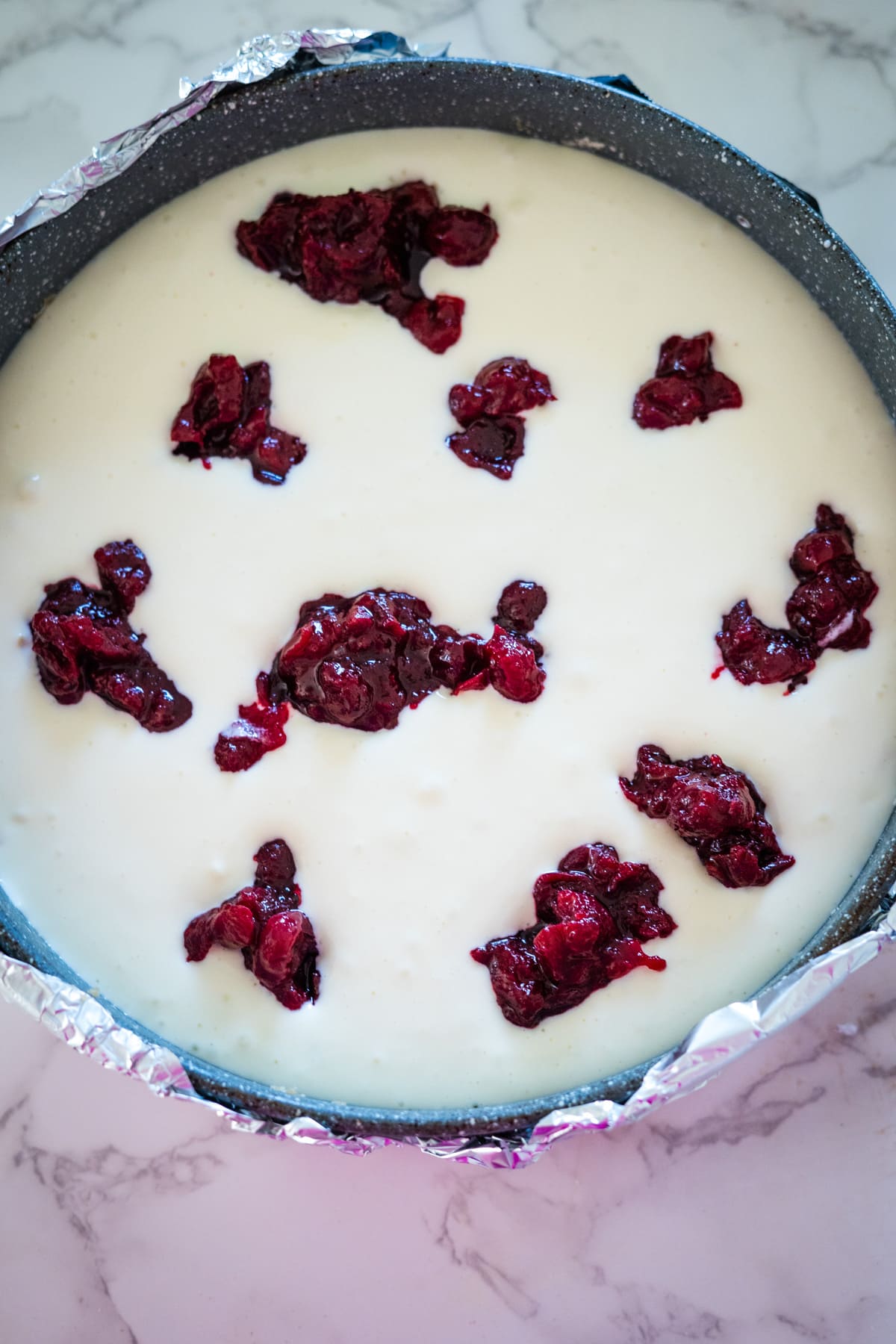 A white pie with cranberries on top, reminiscent of a cranberry cheesecake.