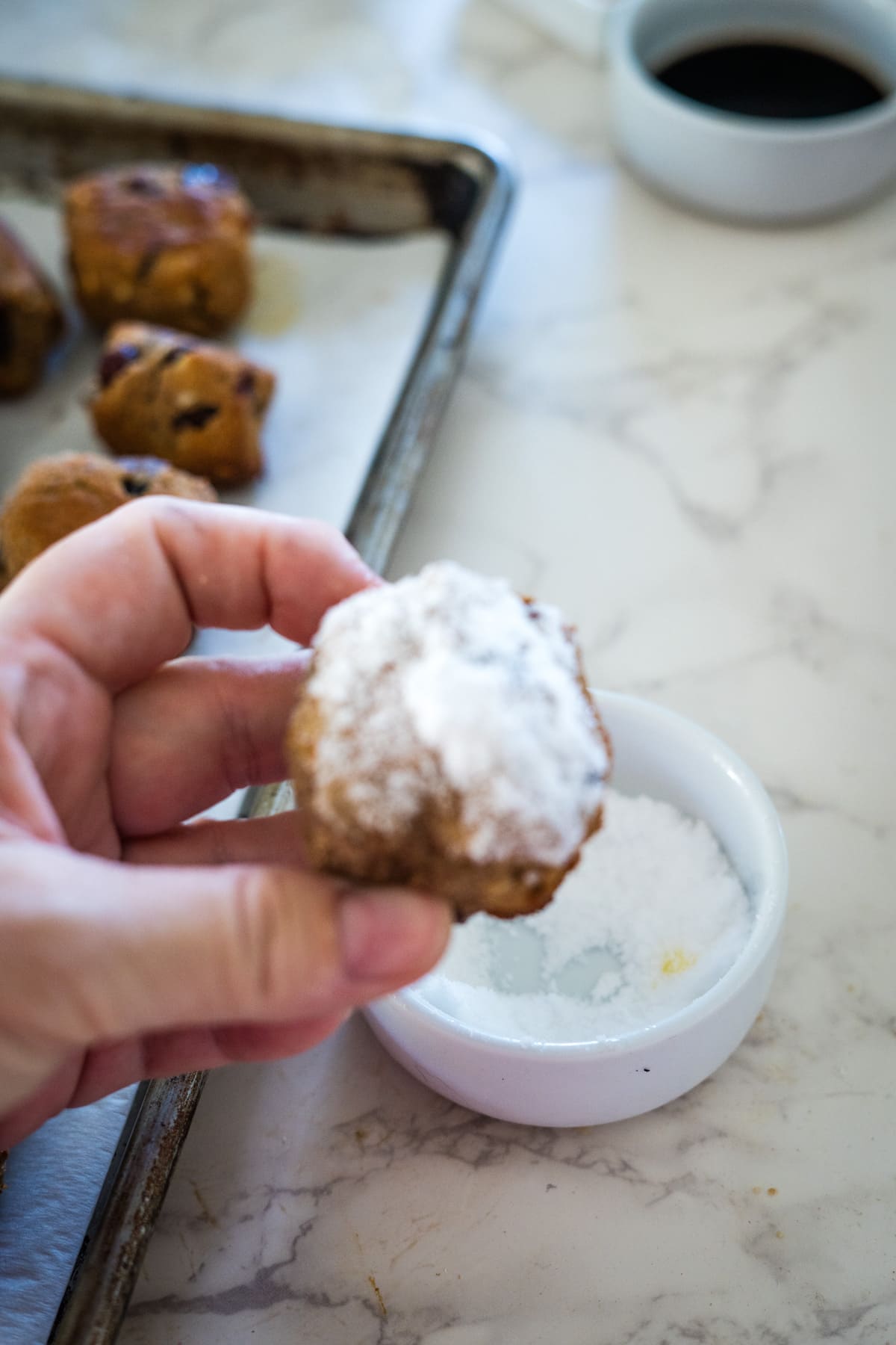 A hand holding a stollen bite with powdered sugar.