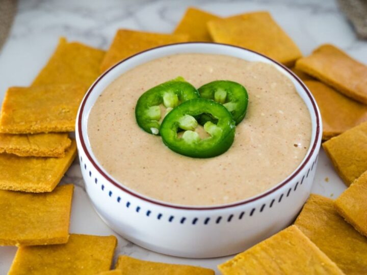 A bowl of jalapeno dip with crackers around it.