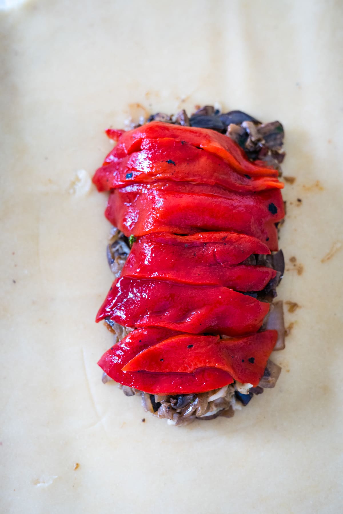 Red peppers are stacked on top of a piece of parchment paper, perfect for making vegetable wellington.