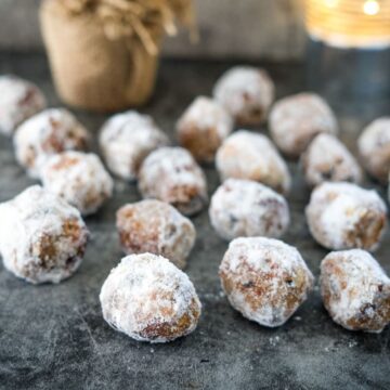 Powdered sugar donuts on a table next to a candle.