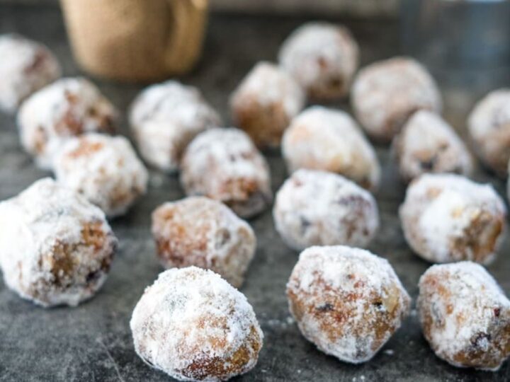 Powdered sugar donuts on a table next to a candle.