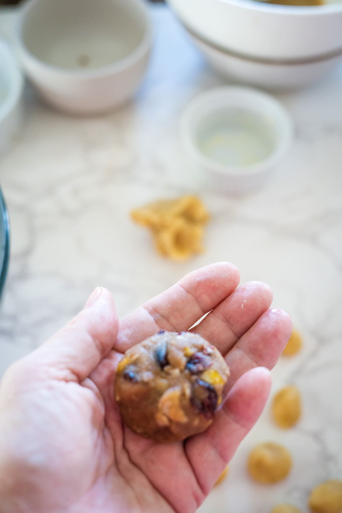 A person holding a stollen cookie in front of a bowl of food.