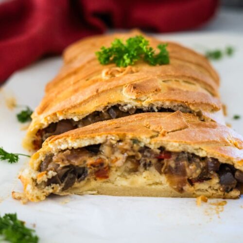 A mushroom stuffed pastry with parsley on a white plate.