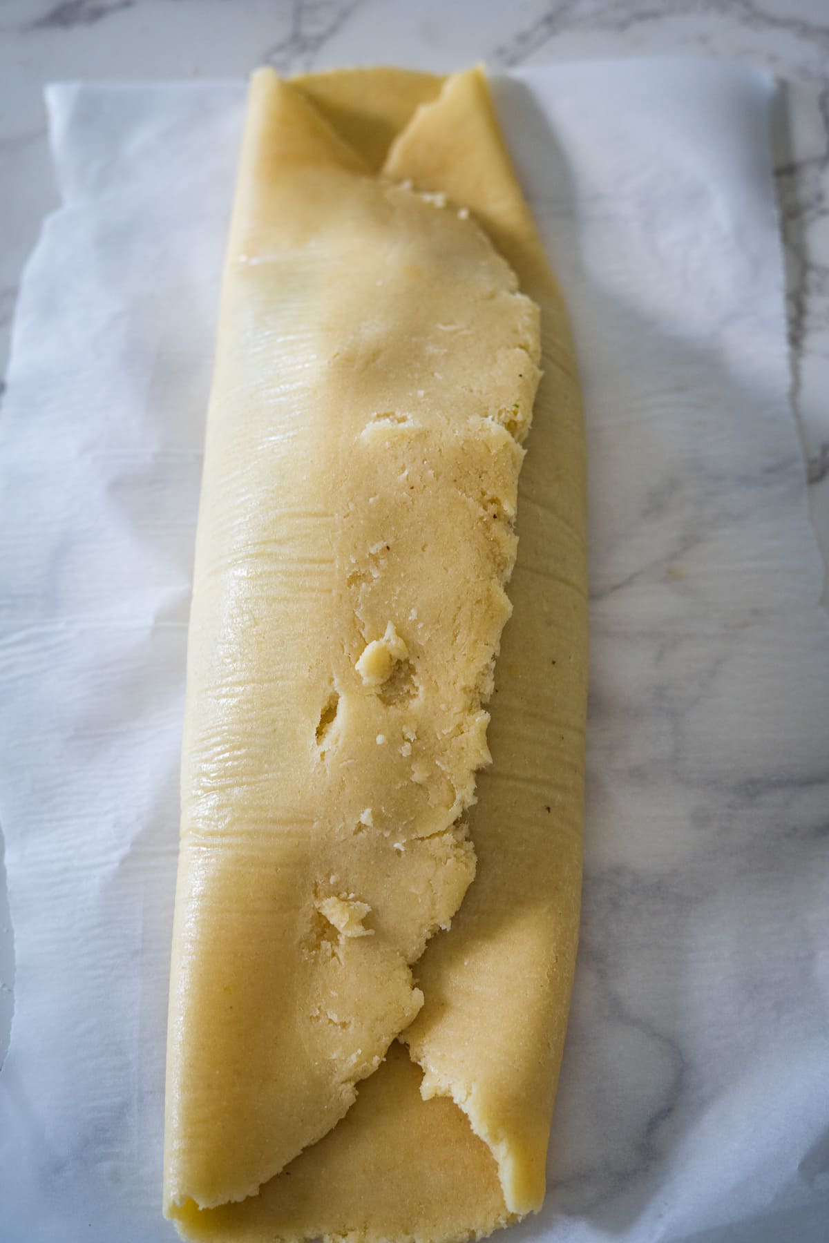 A piece of vegetable Wellington dough is sitting on top of a piece of parchment paper.