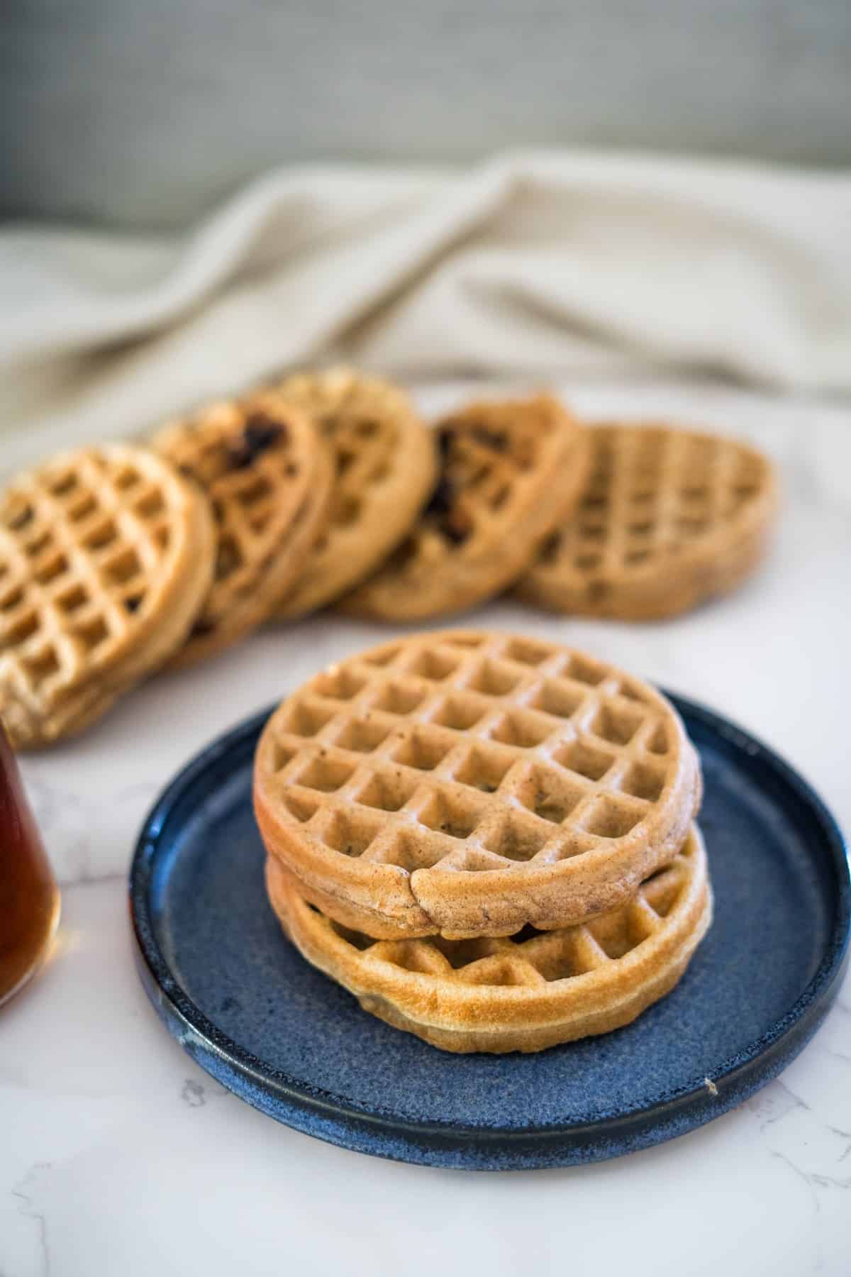 Peanut butter waffles on a plate next to a bottle of honey.
