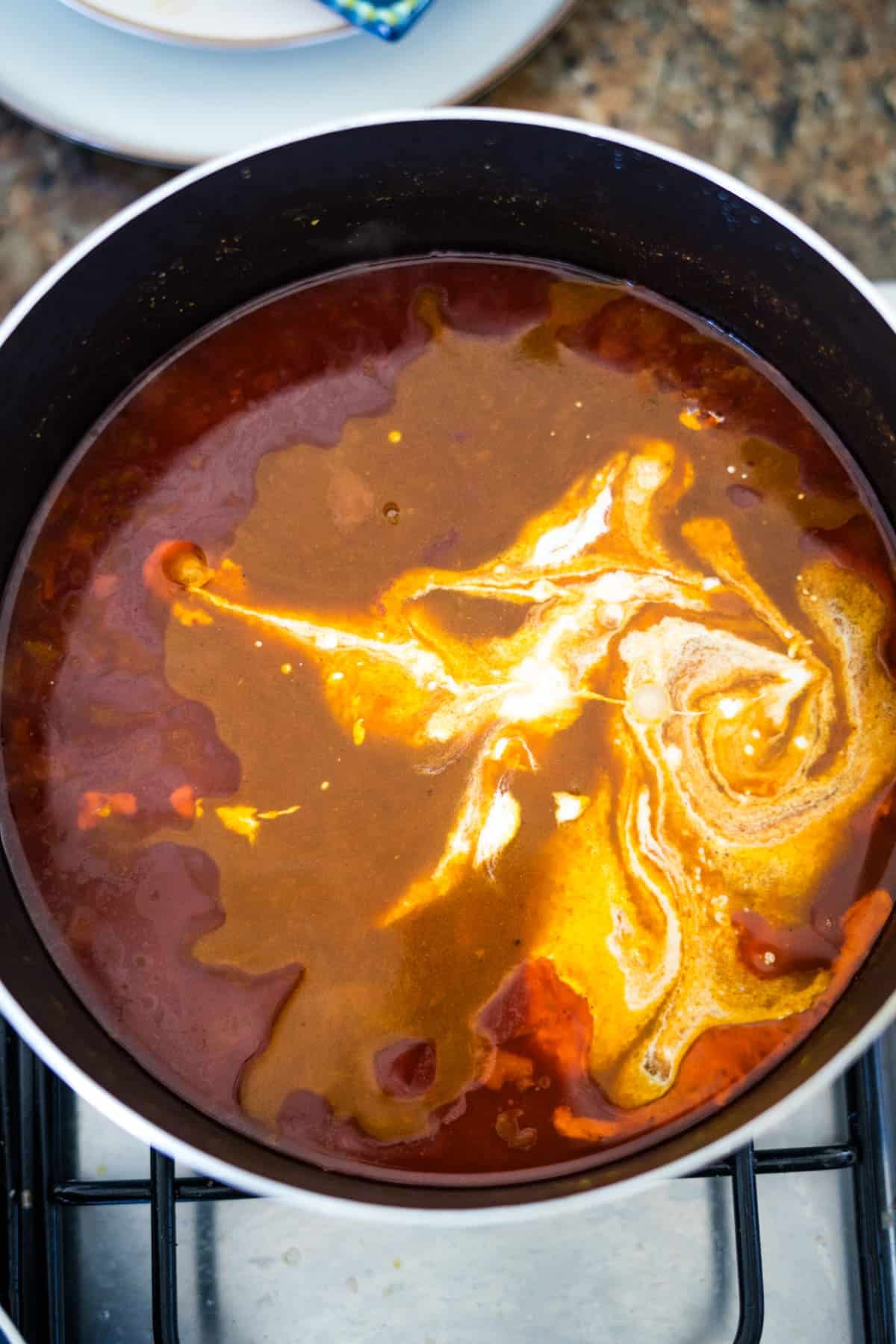 A pot of chicken tikka masala soup simmering on a stove top.