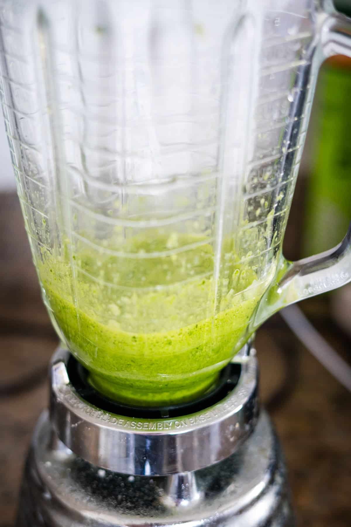 A blender filled with green spinach liquid.