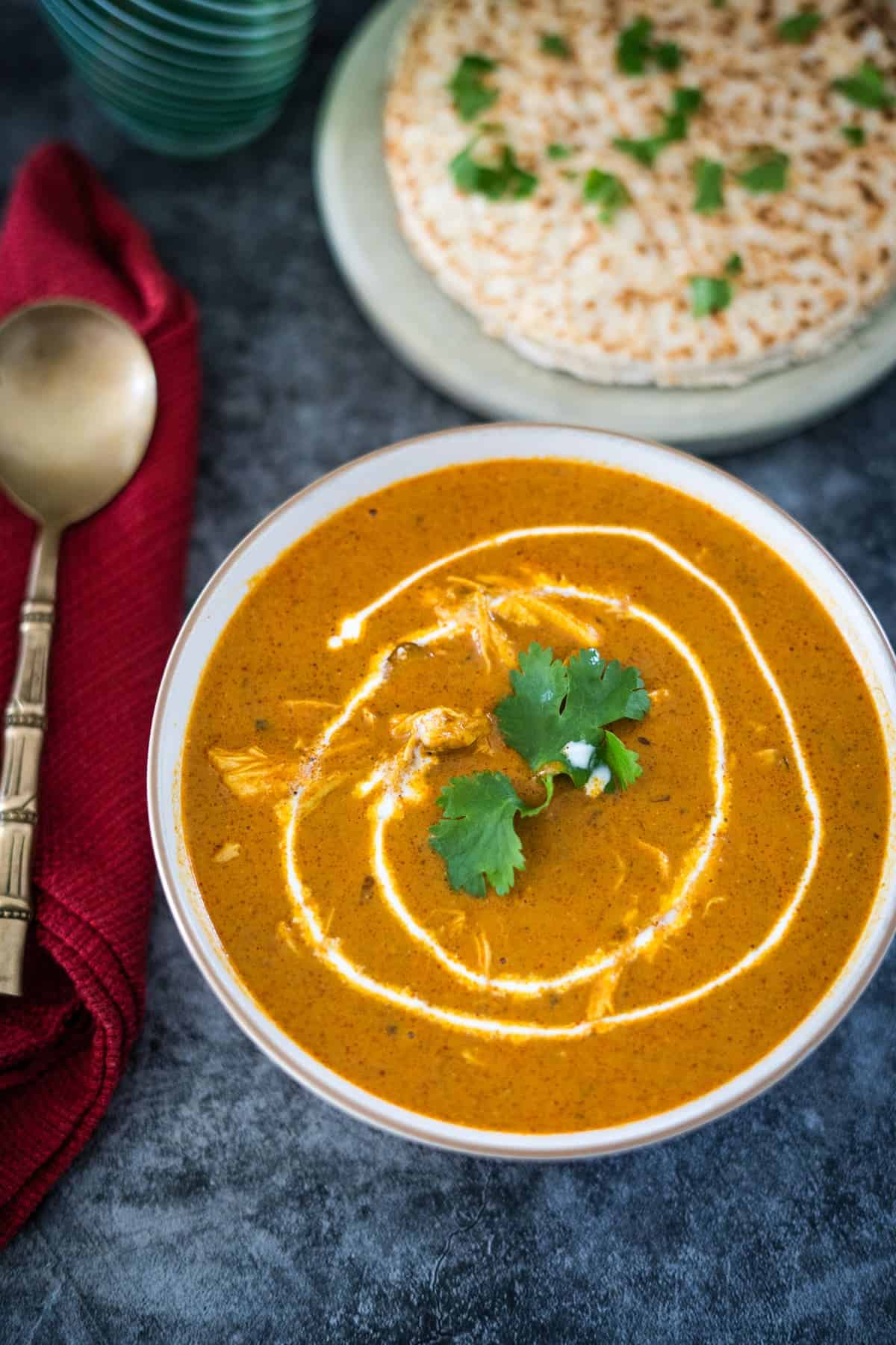 A bowl of soup with a spoon and tortilla.