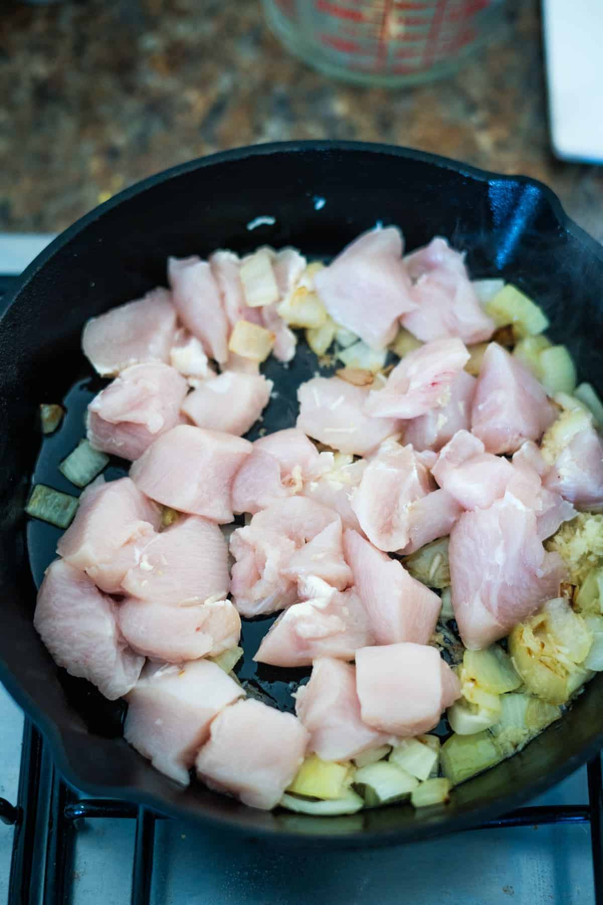 Chicken pasanda cooked with onions in a frying pan.