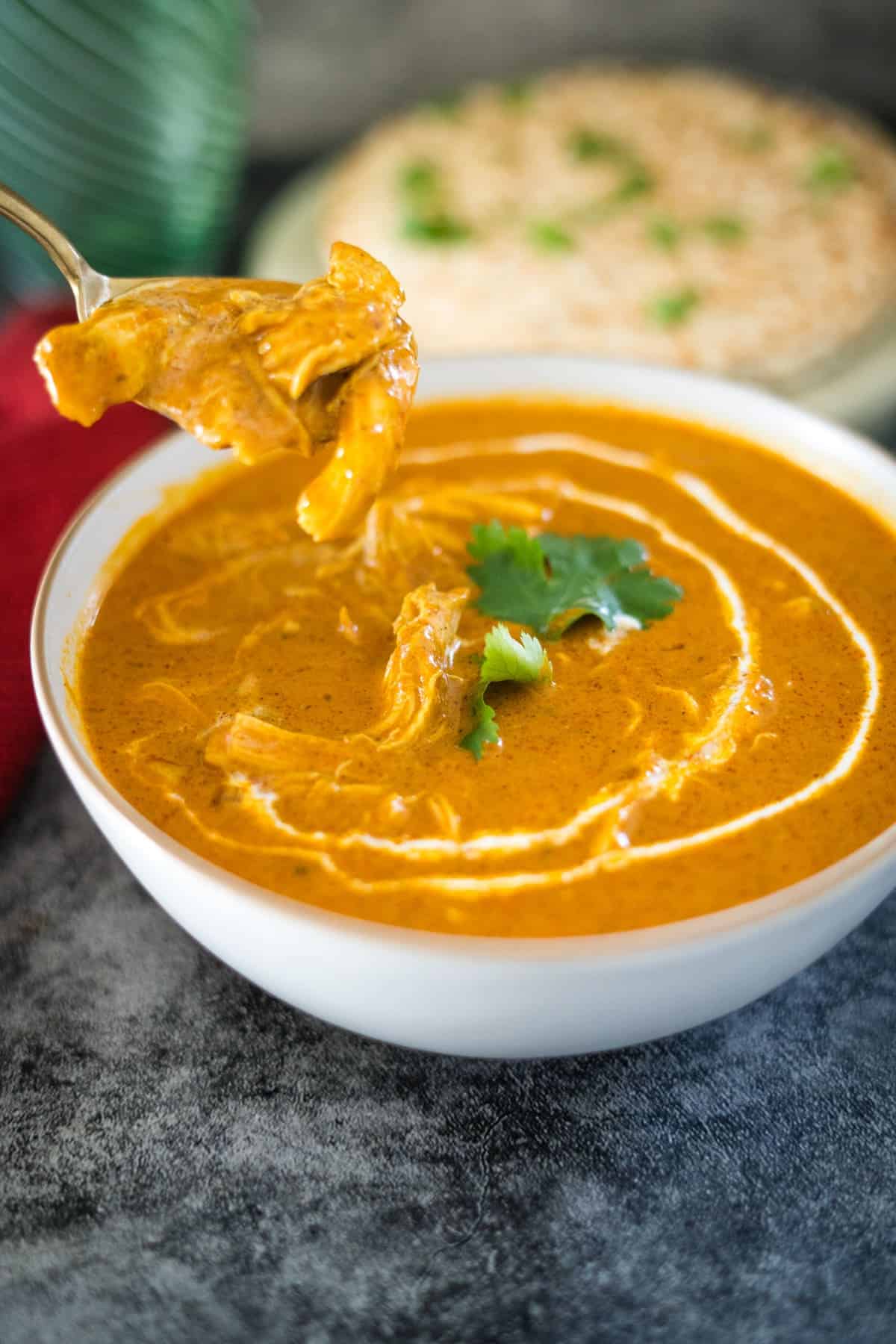 A bowl of chicken tikka masala soup with a spoon.