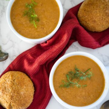 Two bowls of soup with bread and dill.
