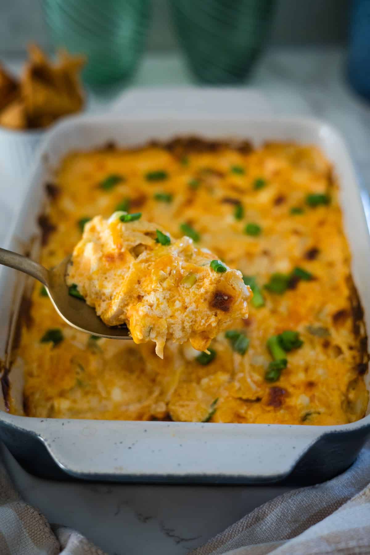 Cheesy buffalo chicken dip in a baking dish with a spoon.