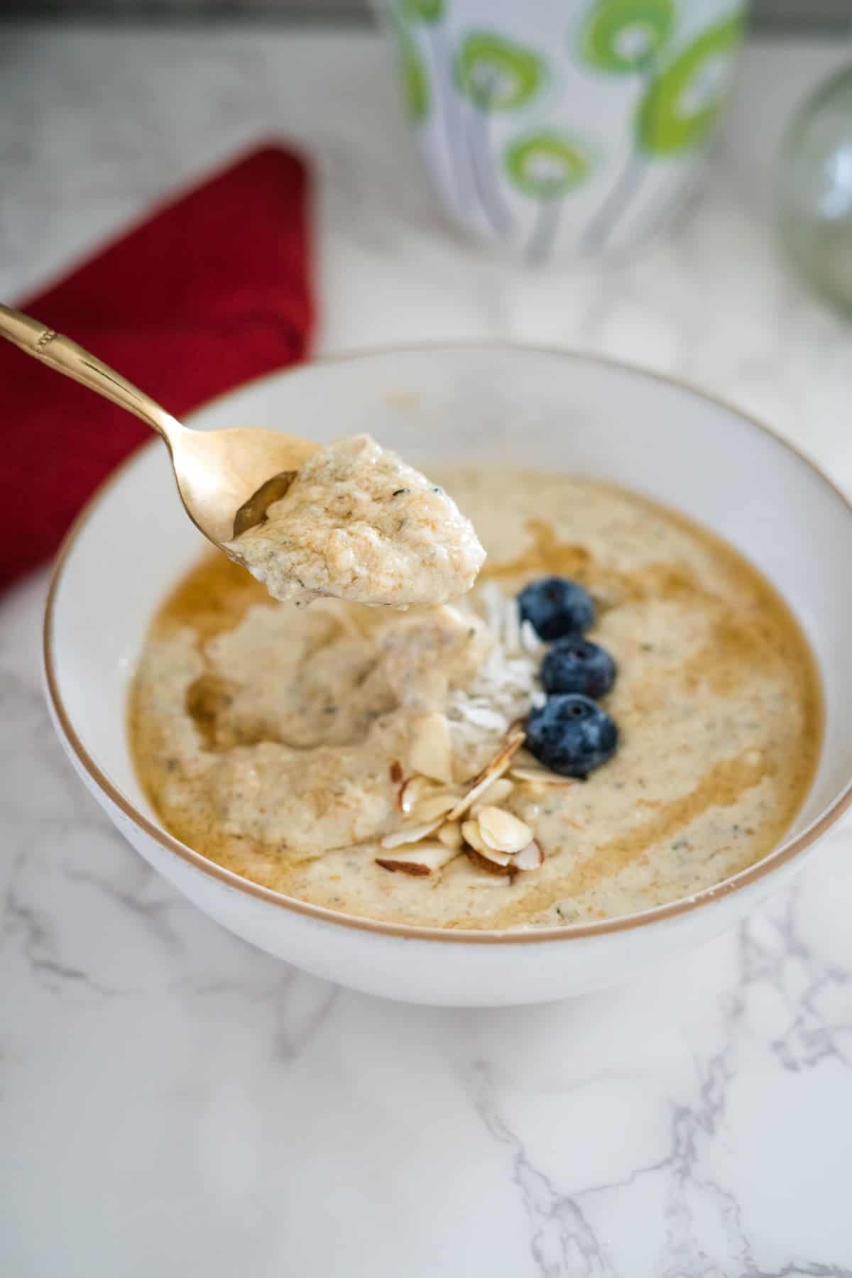 A spoon in a bowl of oatmeal with blueberries and nuts.