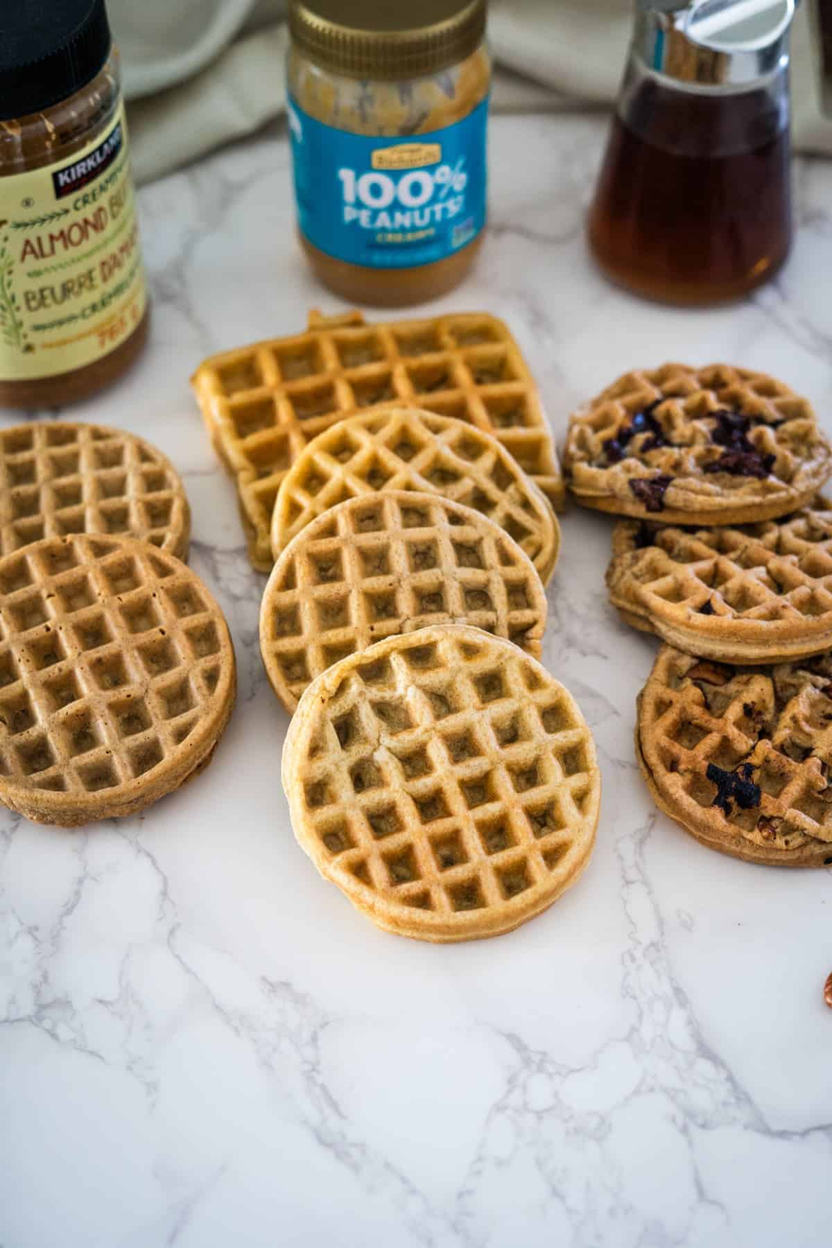 Waffles with peanut butter spread on top, sitting on a marble table.