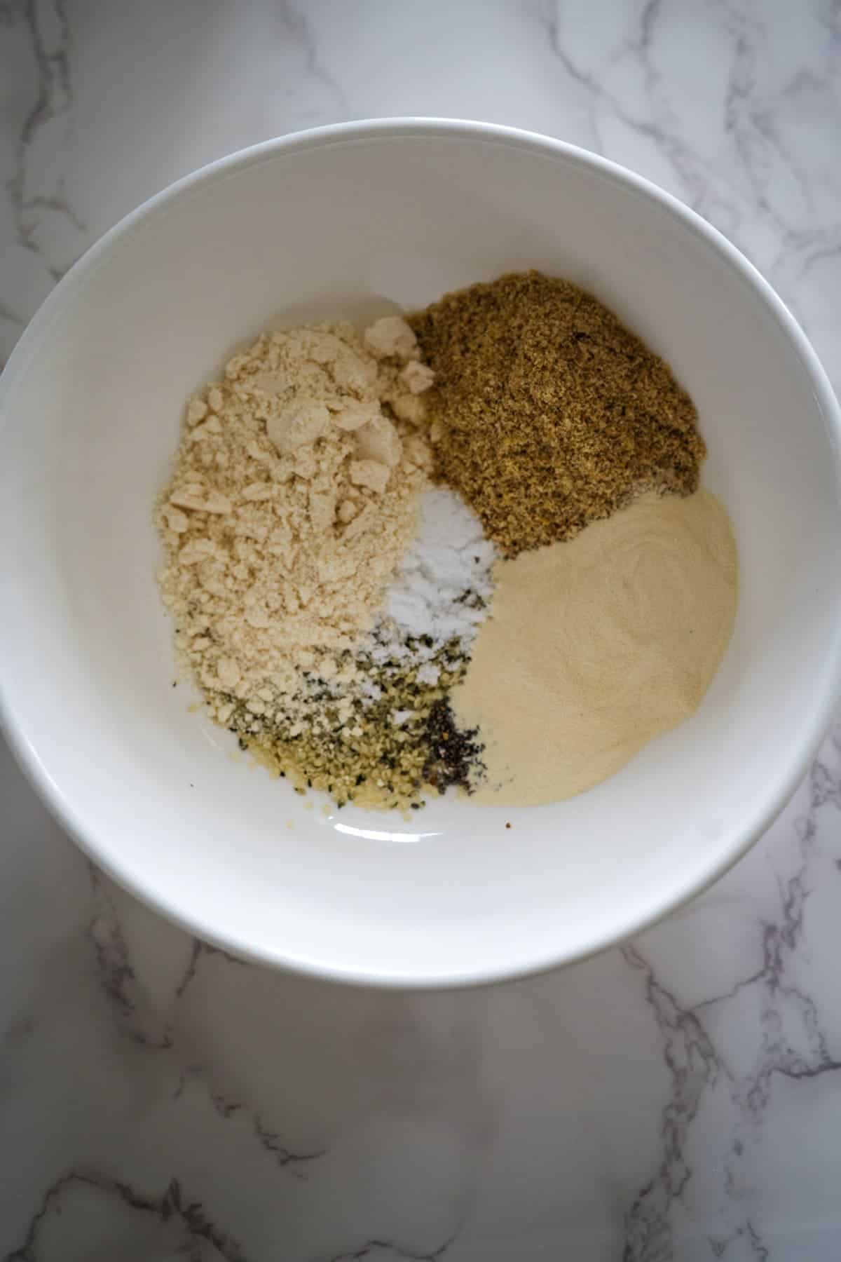 A white bowl with protein porridge and seasonings in it.