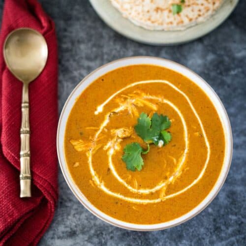 A bowl of soup with a spoon and a napkin.