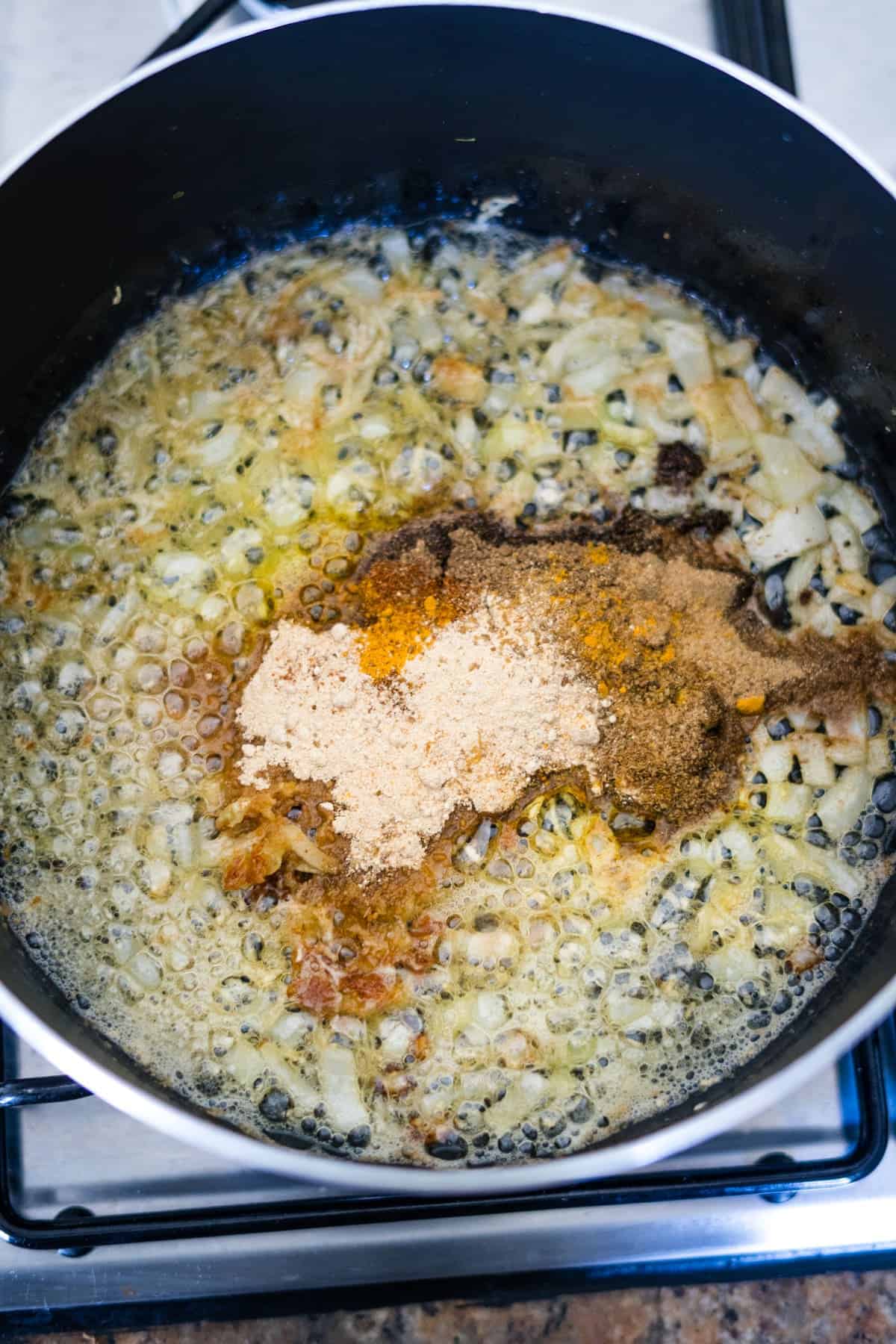 A sizzling chicken tikka masala frying pan on a stove top.