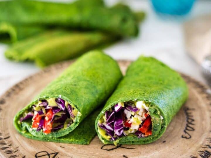 Two green wraps on a wooden cutting board.