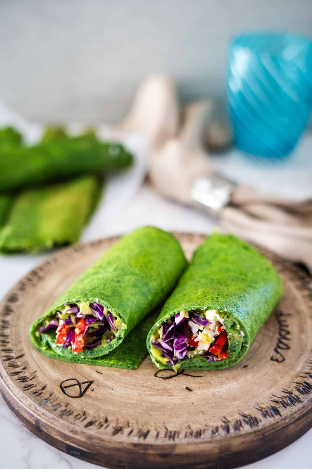 Two green wraps on a wooden cutting board.