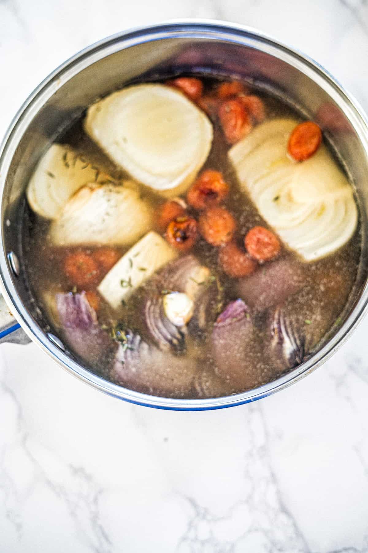 A pot of soup with onions and carrots in it.