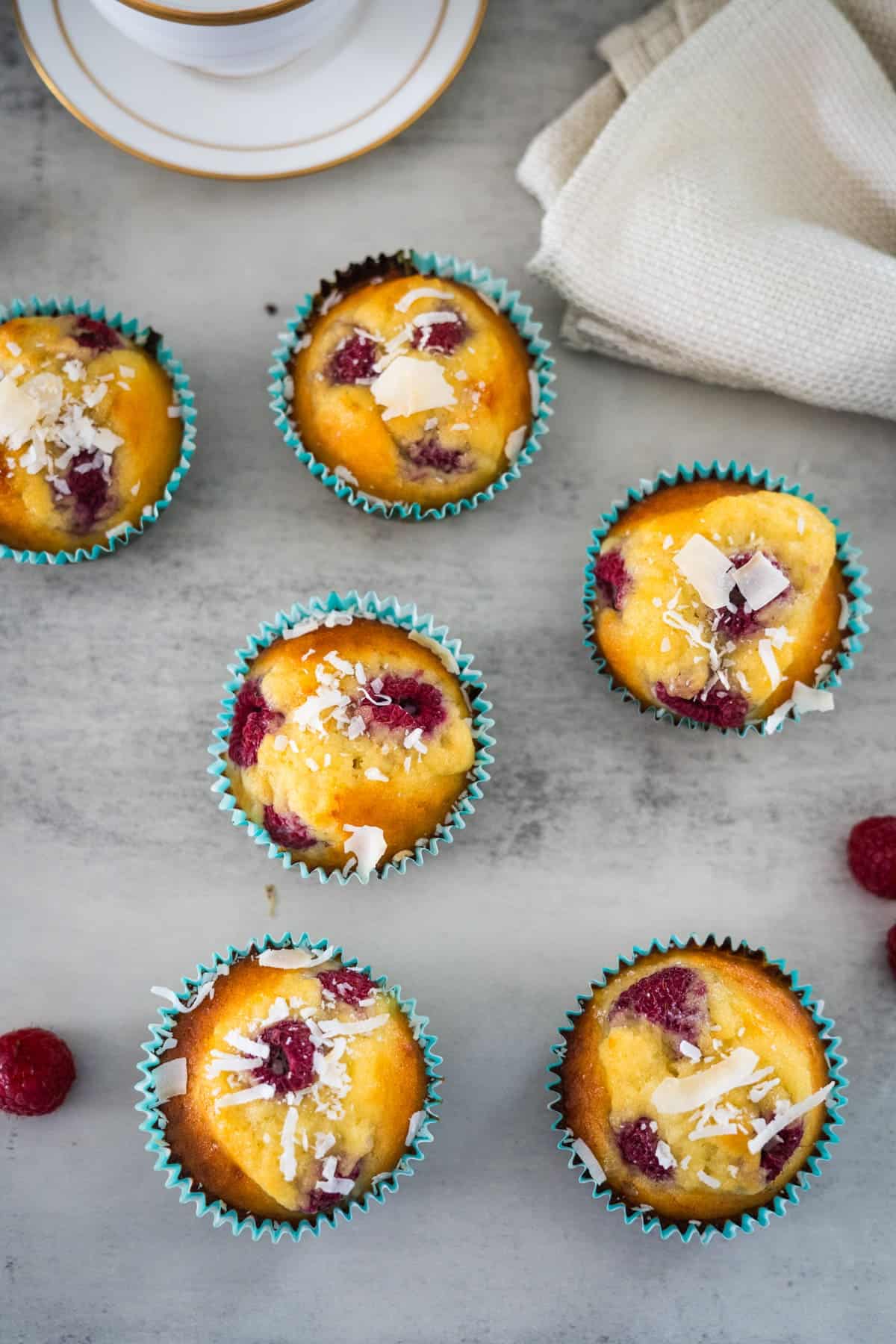 A group of **keto** muffins with raspberries and coconut flakes.