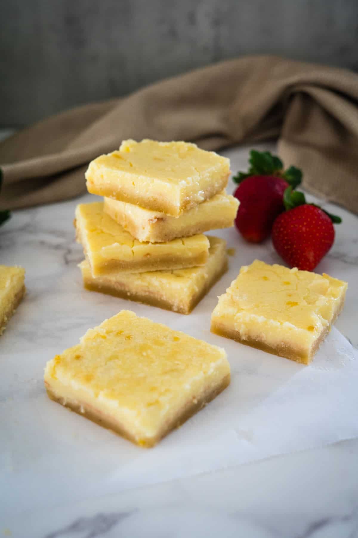 A stack of lemon bars with strawberries on top.