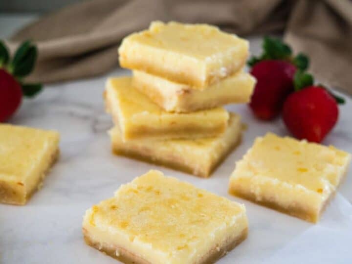 A stack of keto lemon bars adorned with fresh strawberries on top.