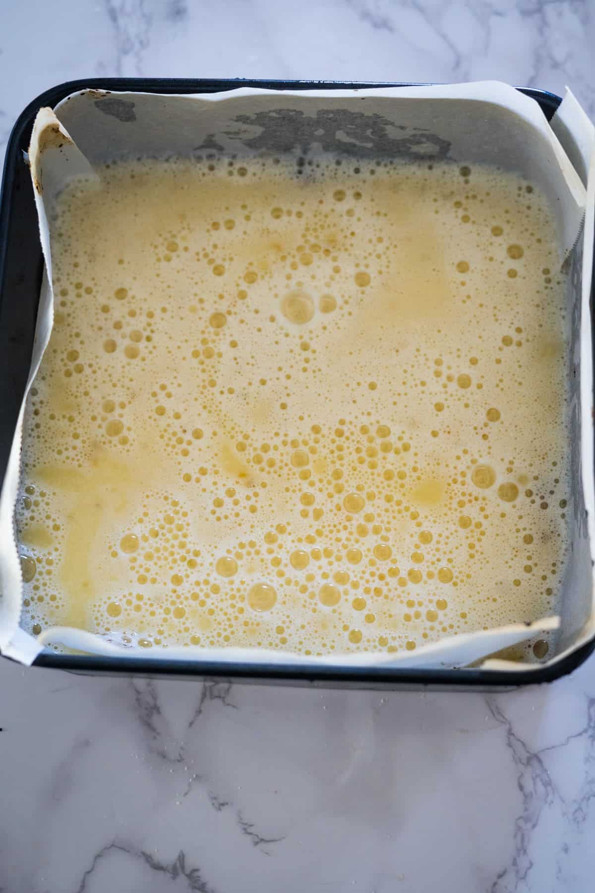 A pan of food with a white paper and yellow liquid.