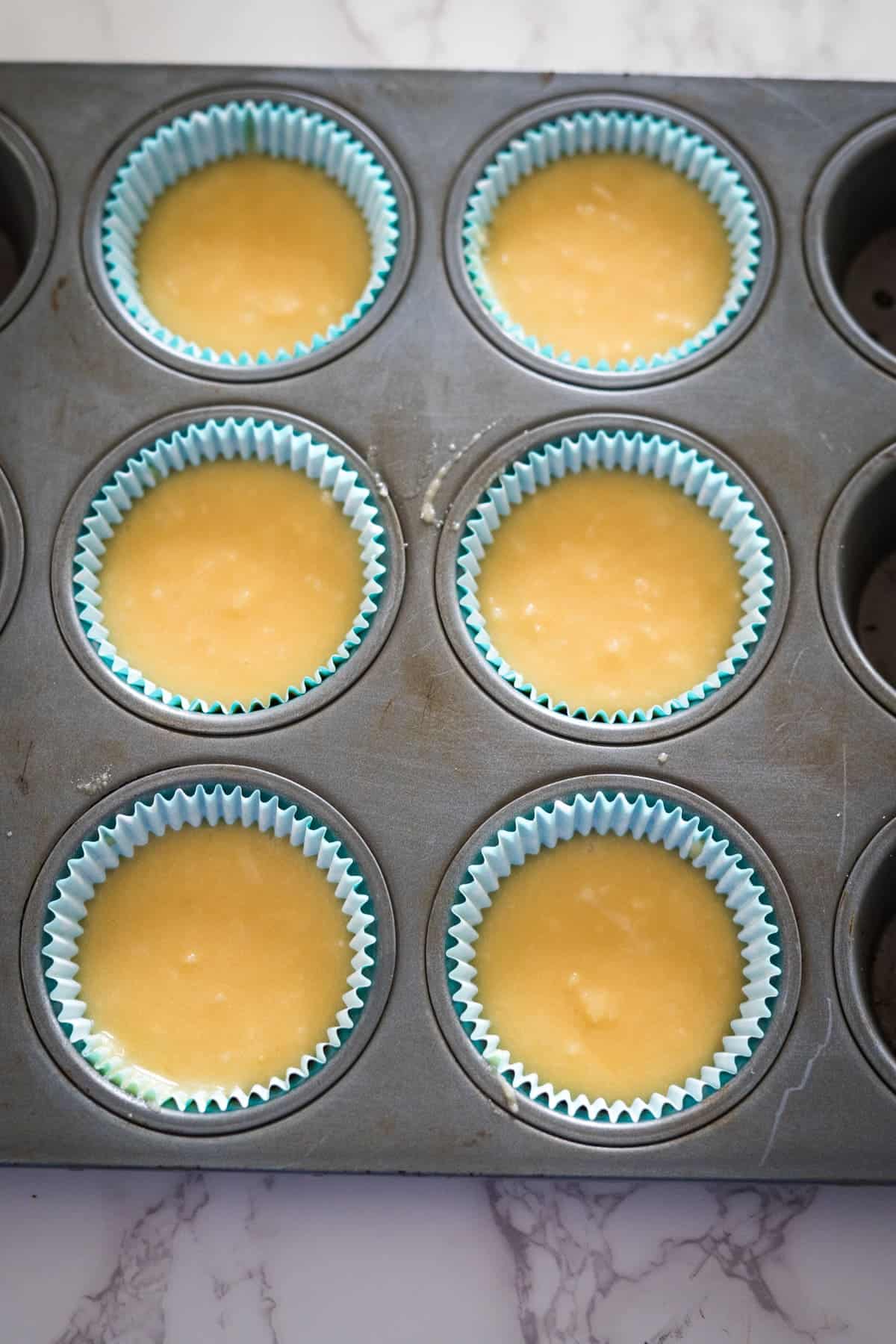 A muffin tin filled with yellow keto cupcakes.