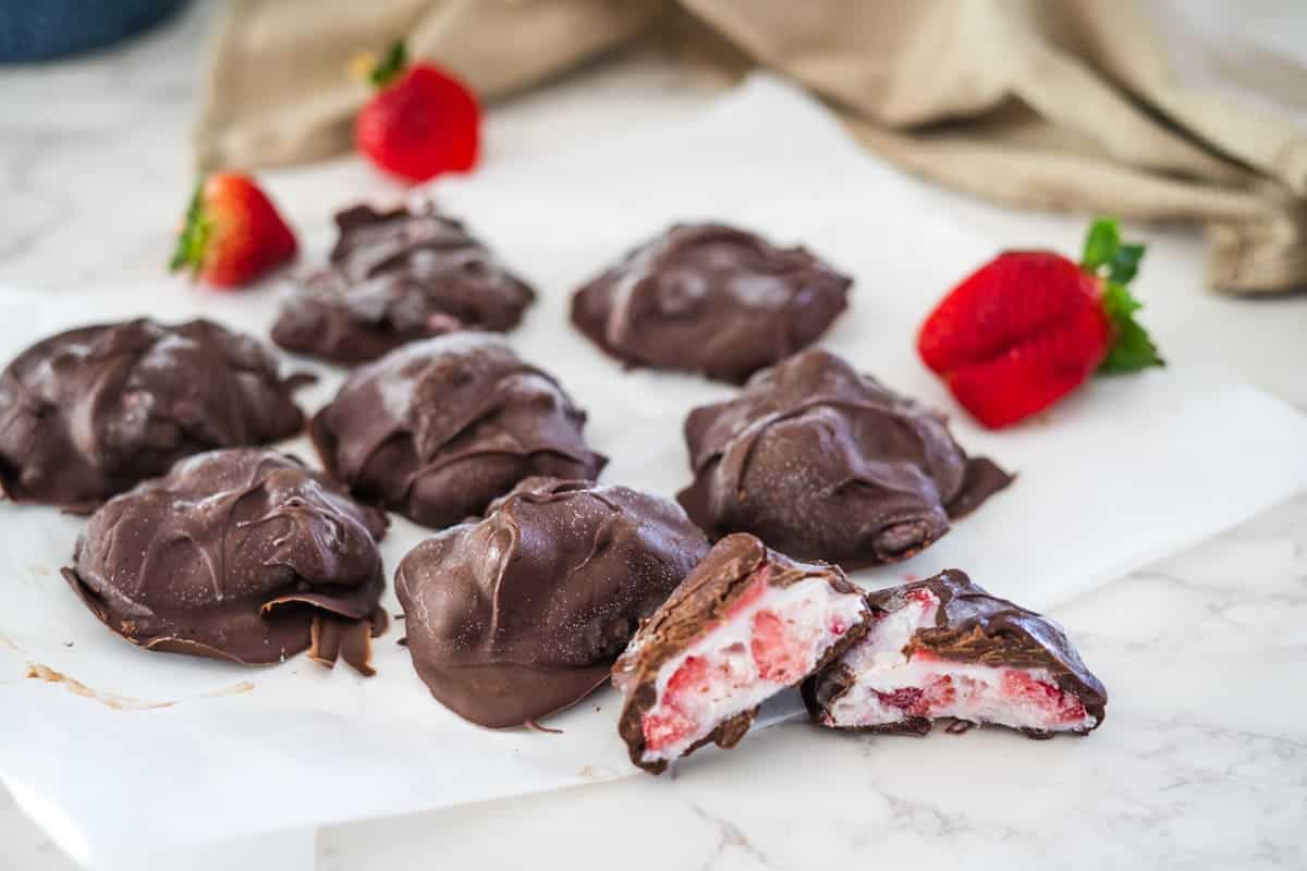 Chocolate covered strawberries sit on a white surface.