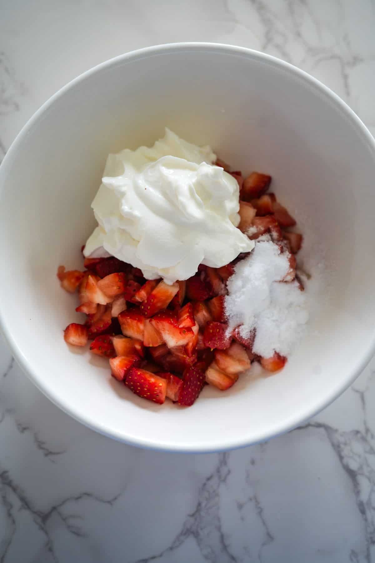 Fresh strawberries and creamy whipped cream in a white bowl.