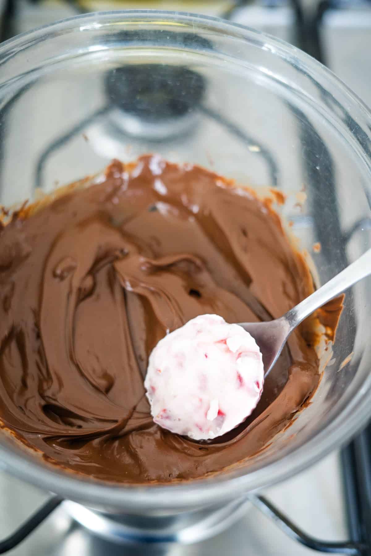 A bowl of rich chocolate ganache topped with a spoon.