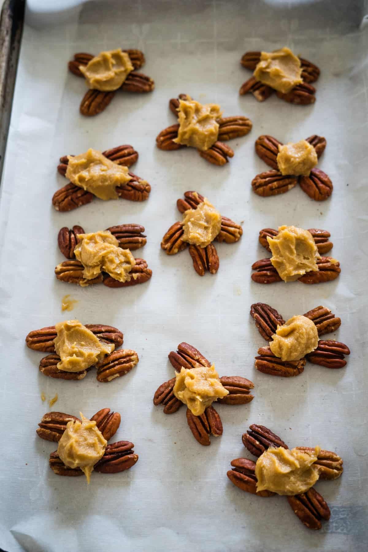 Freshly baked keto pecan cookies on parchment paper, arranged in rows.