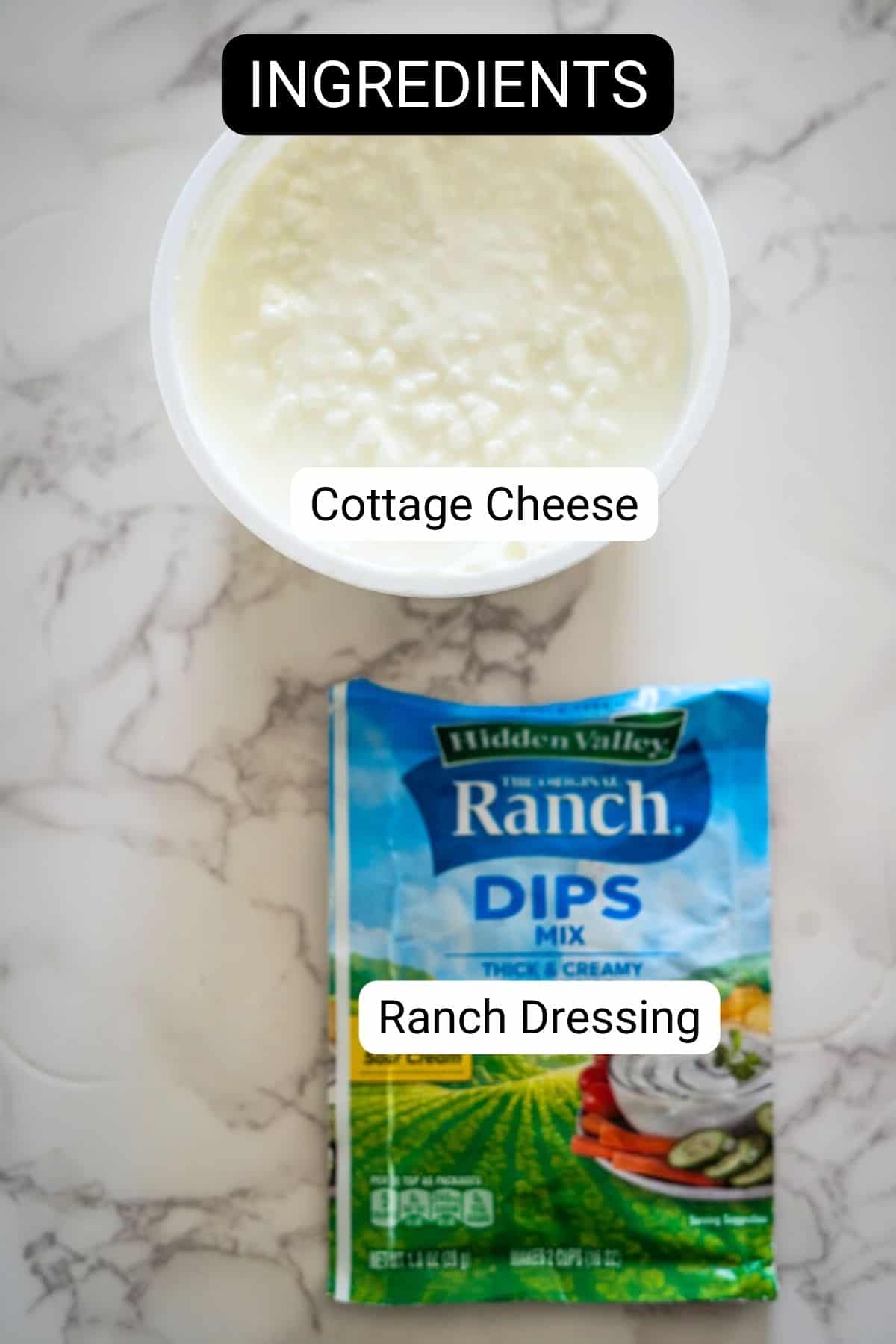 Container of cottage cheese and a packet of ranch dressing mix on a marble surface with a label reading "ingredients.