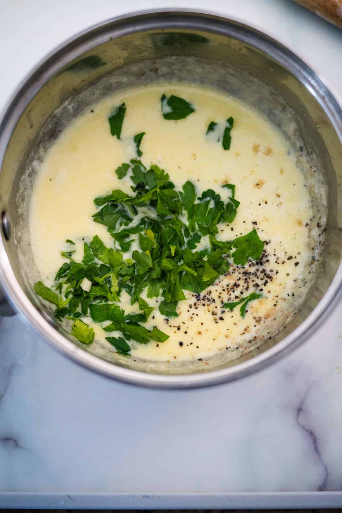 A bowl of salmon in lemon creamy sauce and herbs on a counter.