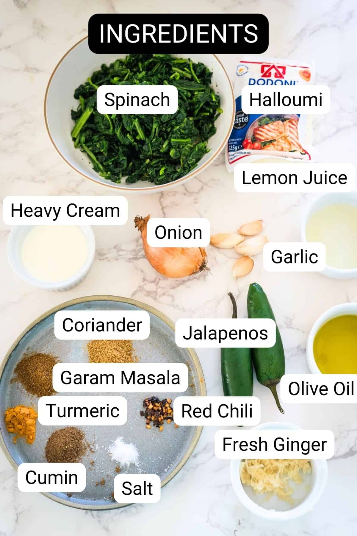 Ingredients for a recipe displayed on a marble countertop, including spinach, halloumi cheese, and various spices and condiments.