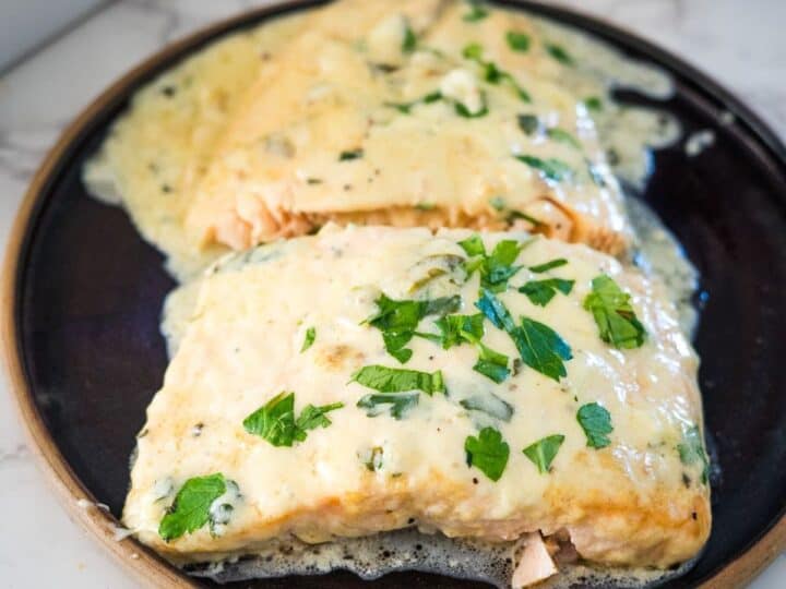 Salmon fillets on a plate with sauce and herbs.